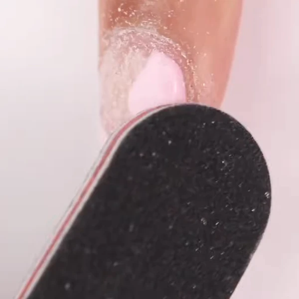 Buffing the top layer of gel nail polish to remove shine before acetone removal