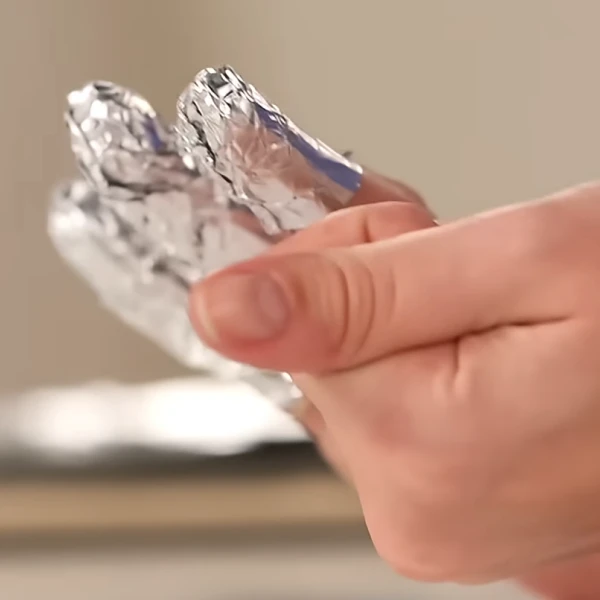 Gel nail polish soaking under foil for 10–20 minutes before removal